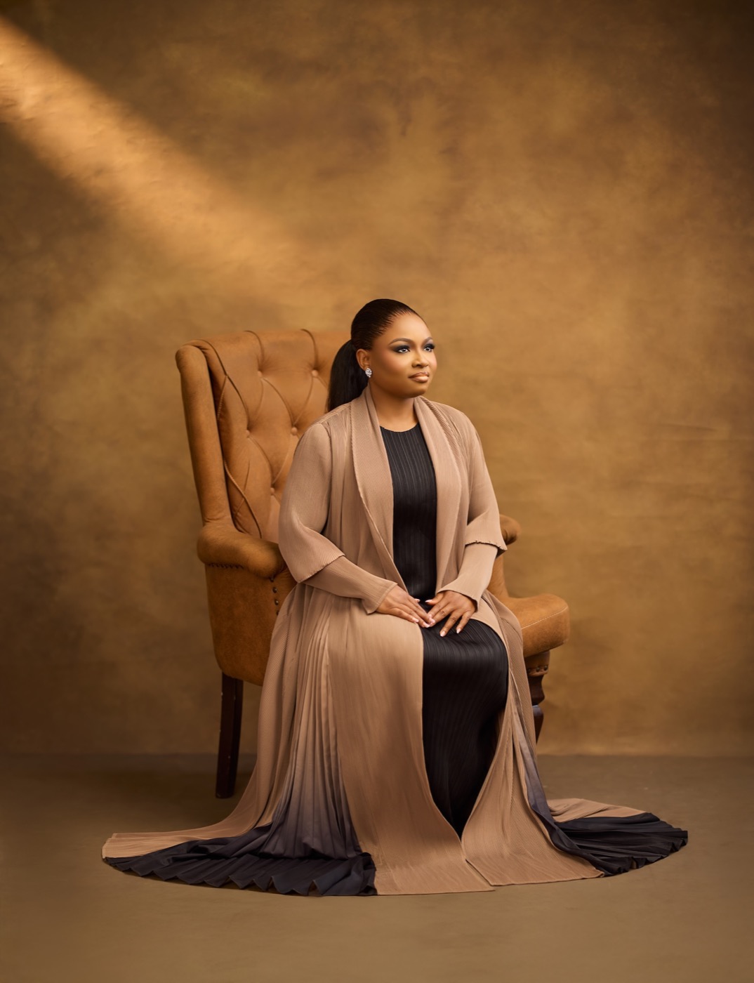 Bessie Nchenge seated in a warm studio portrait