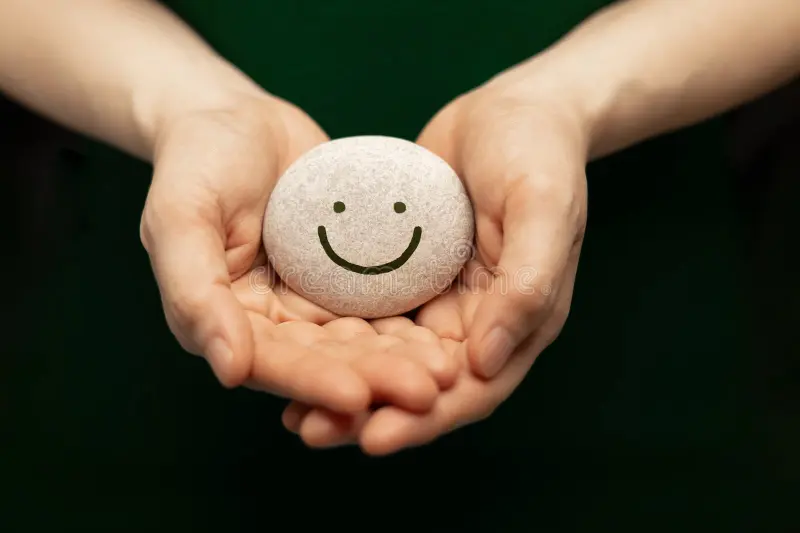 Hands holding a small stone with a gentle smile
